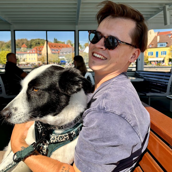 Dave Zimmermann lachend mit seinem Hund auf einer Bootsfahrt
