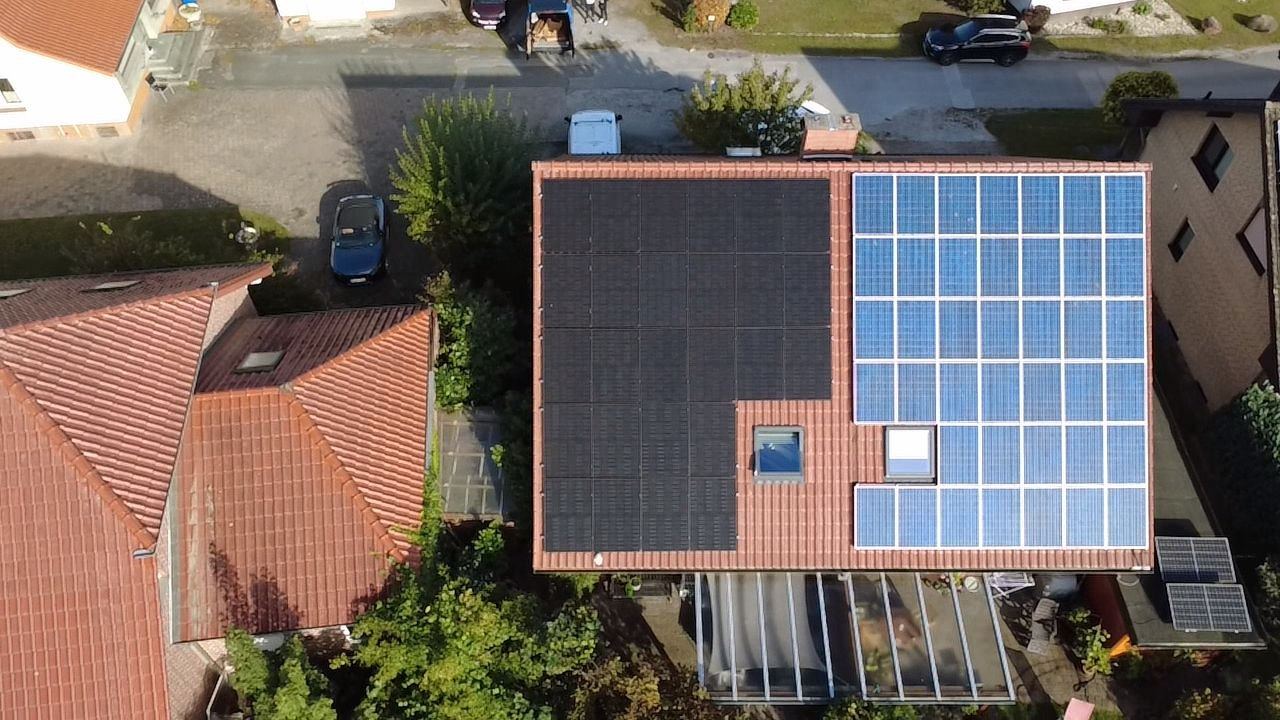 Luftaufnahme eines Dachs mit schwarzen und blauen Solarmodulen